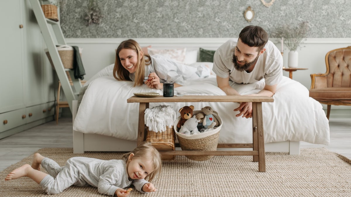 A joyful family bonding in a cozy bedroom, featuring a playful child and loving parents.